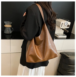 Brown large capacity hobo shoulder bag shown on model in a modern kitchen setting