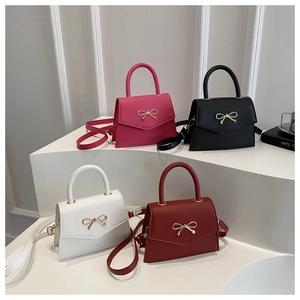 Detailed view of mini square handbags in four colors with decorative metal bow accents