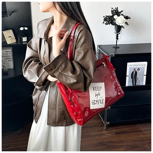 Close-up of red glossy tote bag with transparent PVC panel and chic ribbon detail