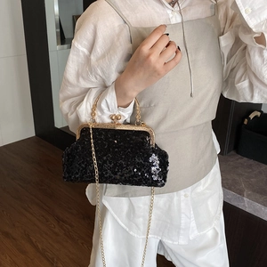 Elegant black sequin evening bag with gold chain strap worn by model in room