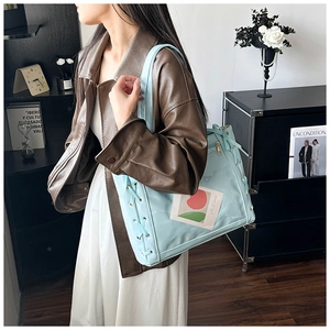 Detail of light blue tote bag featuring decorative ribbon lacing and clear card slot