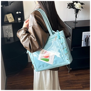 Close-up of light blue tote bag featuring transparent PVC panel and side ribbon bow detail