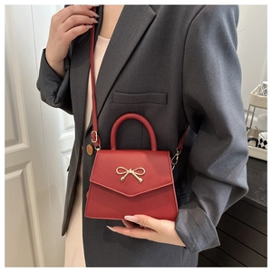 Detail showing red PU leather crossbody bag with golden bow buckle and top handle