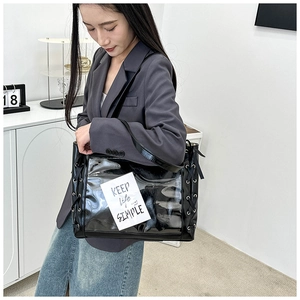 Detail of a black PU and PVC tote bag featuring side lace-up design and a clear front pocket