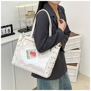 Close-up of white patent leather tote bag with ribbon detail and transparent pocket