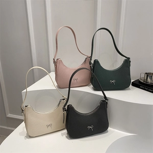 Chic crescent shoulder bags with bow accents in four colors on a tiered display stand