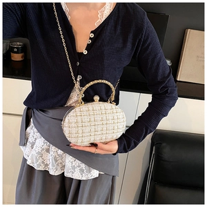 Detail of white tweed box bag featuring gold chain and rhinestone spherical clasp
