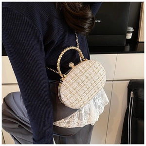 Dettaglio della borsa a conchiglia in tweed con chiusura in strass e catena dorata su modella
