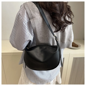 Lifestyle-Ansicht einer schwarzen Halbmond-Tasche getragen zu einem Streifenhemd