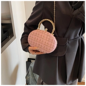 Dettaglio borsa da sera in tweed rosa con manico circolare dorato e chiusura a perla