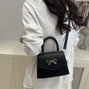 Elegant black handbag with golden bow metal clasp and leather handle for women