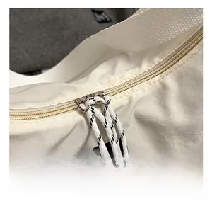 Detail of high-quality golden metal zipper with black and white woven rope pullers on tote bag