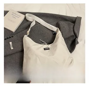 Detail of minimalist cream canvas shoulder bag with black Fashion label and wide strap