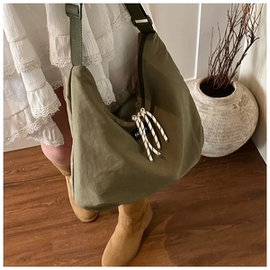 Detail of army green canvas crossbody bag featuring adjustable strap and fashion label