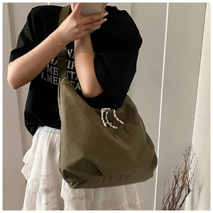 Detail of olive green nylon tote bag with drawstring closure and wide shoulder strap