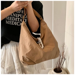 Detail of khaki canvas tote bag featuring fashion label and braided rope accent