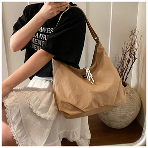 Detail of khaki canvas tote bag with woven drawstring and textured shoulder strap