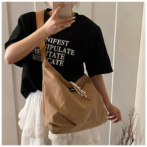 Detail of khaki nylon tote bag featuring drawstring detail and fashion letter patch