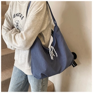 Detail view of large blue hobo bag with striped zipper cords on model in natural light