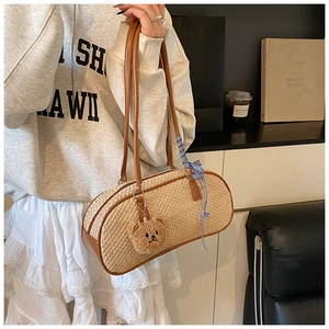 Detail of woven straw shoulder bag with leather handles and cute bear charm accessory