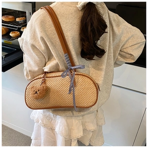 Close-up of woven shoulder bag with ribbon bow and bear charm in a kitchen setting