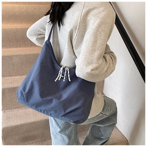 Detail of blue canvas tote bag featuring drawstring side and fashion brand label