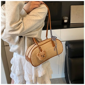 Detail of straw shoulder bag with leather handles and cute bear charm accessory