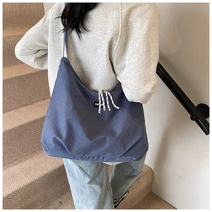 Close-up of blue canvas tote bag with white FASHION logo tag and textured drawstring details
