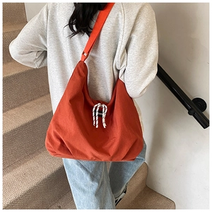 Modern brick red canvas hobo bag worn crossbody showing spacious capacity and trendy design