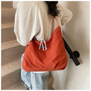 Detail of orange nylon tote bag with fashion tag and woven rope decoration