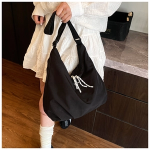 Detail of a large black canvas tote bag with woven drawstring accents for daily commute