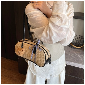 Close-up of woven cylinder shoulder bag featuring black straps and plush bear charm