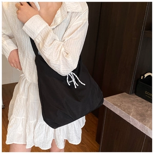Detailed view of black nylon crossbody bag with fashion label on white shirt dress