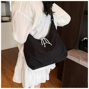 Detail of black large capacity canvas crossbody bag with white decorative drawstring