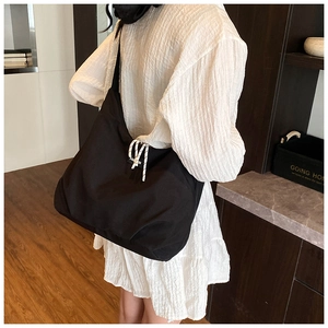 Detailed view of the large black canvas tote bag with woven rope decor on model