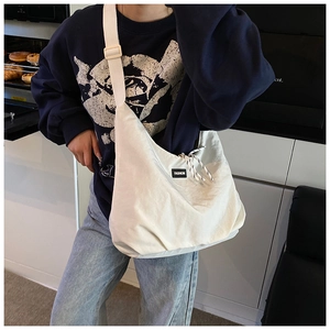 Detail view of cream oversized crossbody bag with fashion label in modern kitchen setting