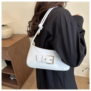 Detail einer weißen Baguette-Tasche mit goldener Schnalle und Knotengurt am Modell