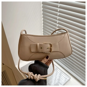Close-up of beige underarm bag featuring large gold buckle and knotted strap detail