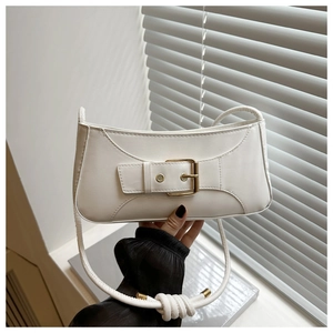 Detail of white leather shoulder bag featuring golden buckle and knotted strap accents