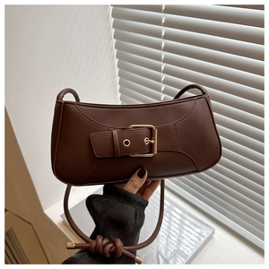 Detail of a brown leather baguette bag featuring a vintage gold buckle and knot accents