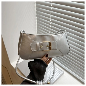 Detail of silver metallic underarm bag with decorative gold buckle and glossy texture