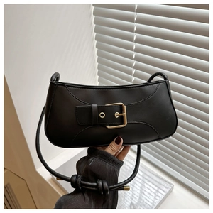 Detail of black faux leather underarm bag with a large decorative gold buckle accent