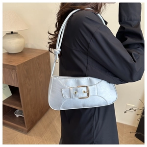 Detail der silbernen Mondsichel-Tasche mit geknotetem Gurt und goldener Schnalle am Outfit