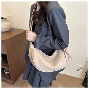 Detail of beige crescent hobo bag with pebble leather texture and adjustable strap