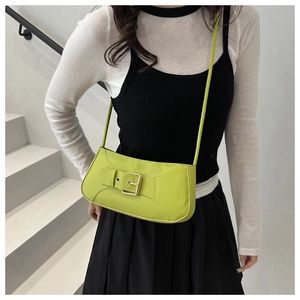 Detail view of neon green baguette bag with adjustable strap and metallic buckle design