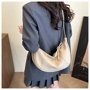 Detail of beige lychee grain leather hobo bag featuring stylish knotted shoulder strap