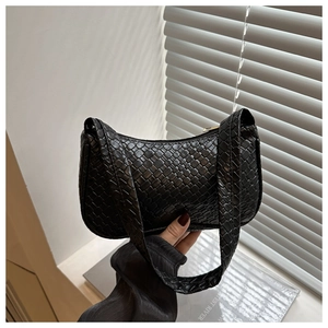 Macro detail of the black woven leather texture on a stylish minimalist hobo handbag
