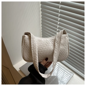 Detailed view of cream woven leather handbag texture on a minimalist home background
