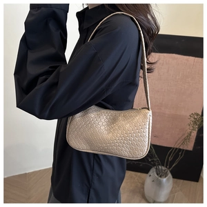 Detail shot of the beige woven square pattern texture on a stylish underarm handbag
