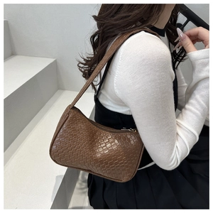 Close-up of brown woven leather texture on a minimalist rectangular baguette shoulder bag
